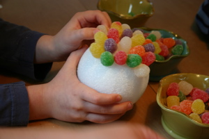 close-up of kid hand adding Gumdrops to styrofoam ornament ball