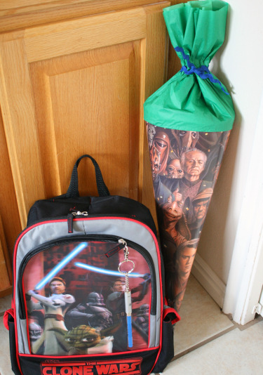 A Star Wars backpack and a Schultüte on the floor in front of a cabinet 