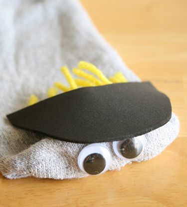 decorating sock puppet with googly eyes, fabric and yarn