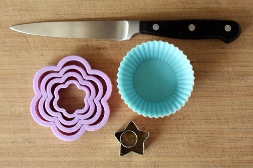 Supplies for making bento boxes on a table (knife, cookie cutters and cupcake paper cups)
