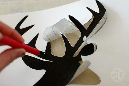 cutting out shape of reindeer from contact paper 