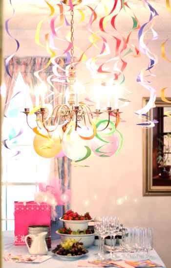 multi color paper streamers hanging from the ceiling in a dining room as party decor