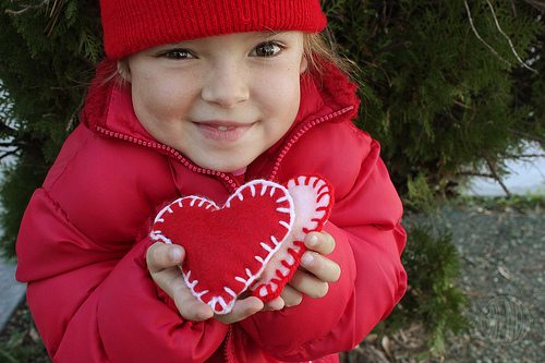 young child holding heart shaped felt hand warmers 