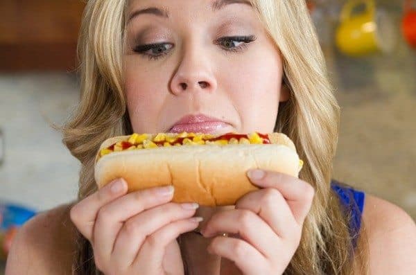 Jennette McCurdy looking down at hot dog in a bun