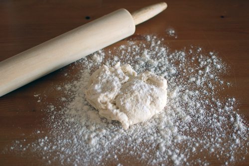 Rolling pin with dough and flour on a counter top