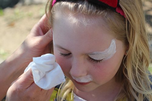 close-up of mom wiping face paint off a girl's face with face wipe