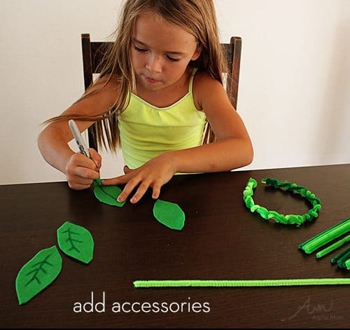 A young girl sitting at a table coloring with black sharpie on green felt