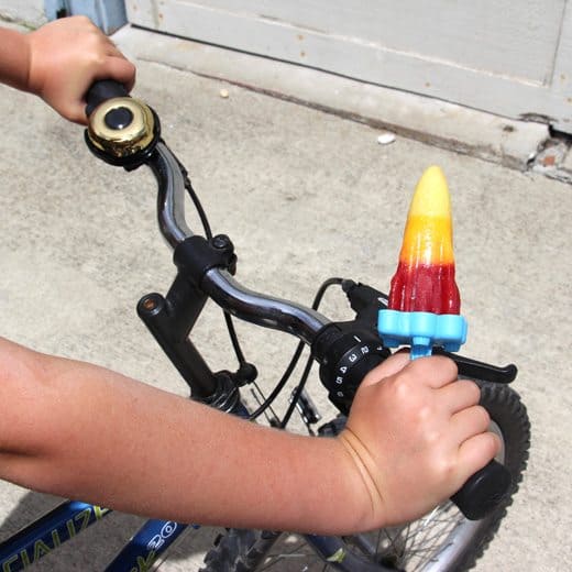 Child on a bike eating a Popsicle 