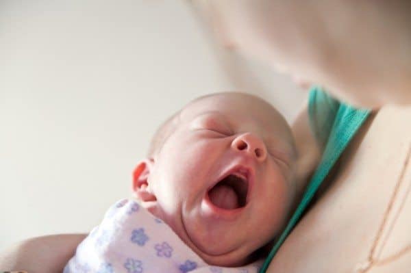 infant yawning while being by mother
