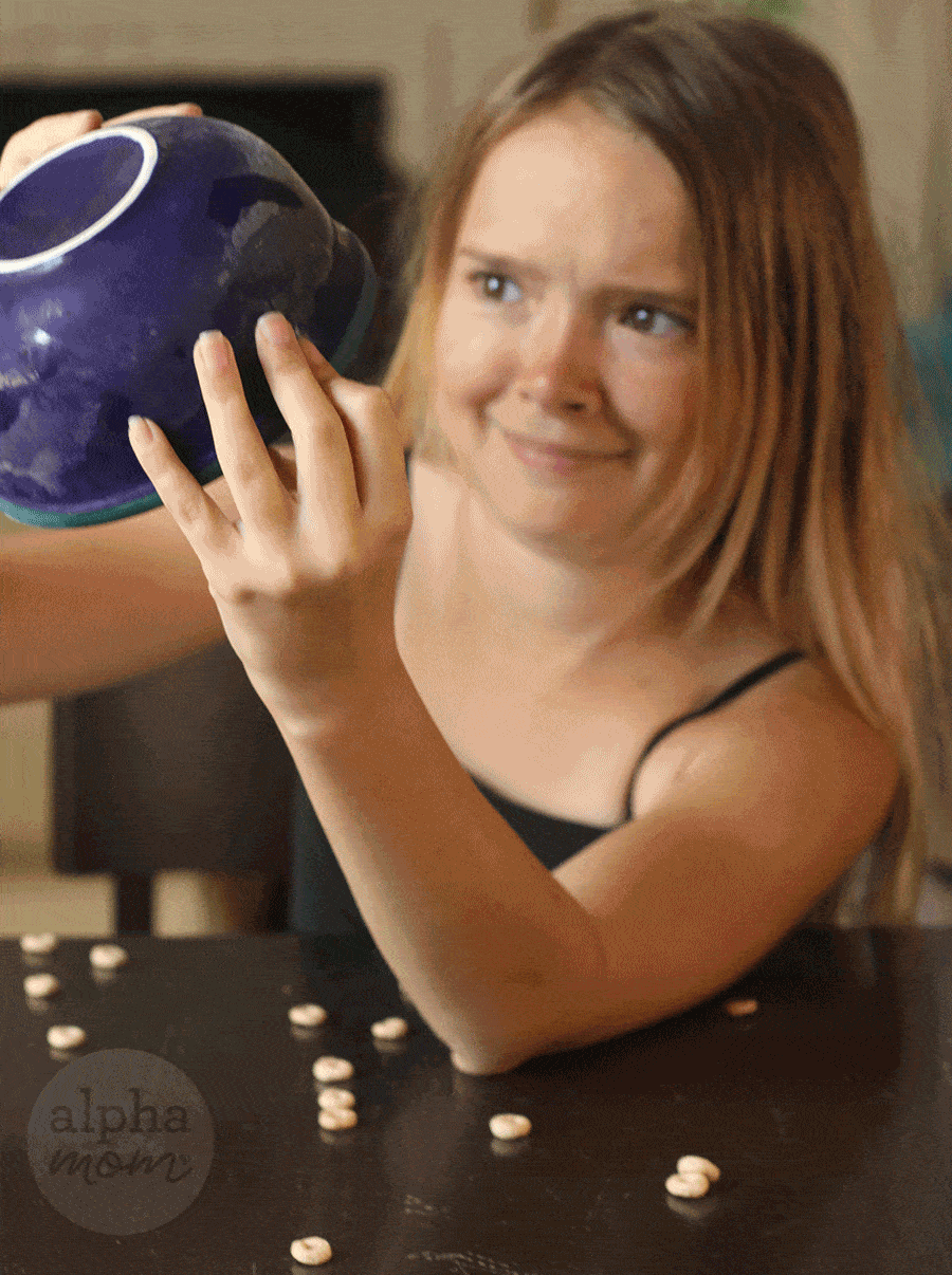 gif of blond girl holding up blue bowl and turning over frozen Cheerios cereal