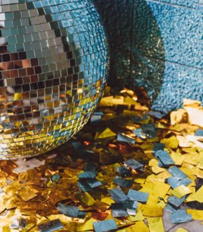 disco ball and silver and gold confetti on the floor resting against a corner