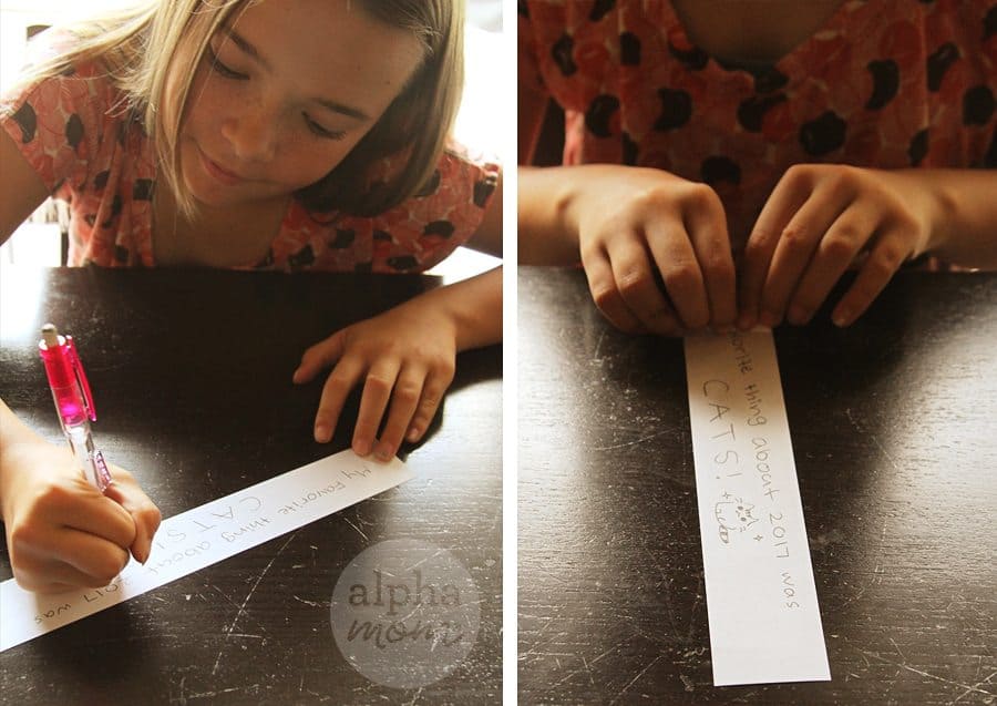 Young girl writing messages from the past year on a piece of paper 