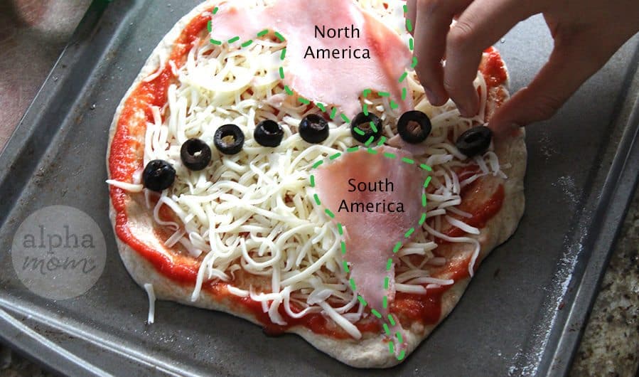 Close-up of kid making pizza with topping so that it looks like Earth to celebrate Earth Day