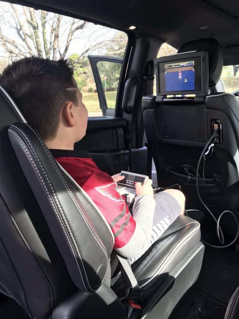 inside of a minivan with a kid playing a video game on an infotainment system