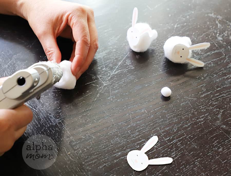 hot glue gun putting bunny faces on cotton balls