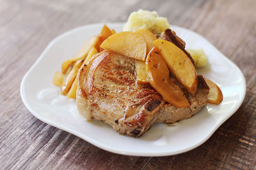 Side view of pork chops and apples on a plate with mashed potatoes