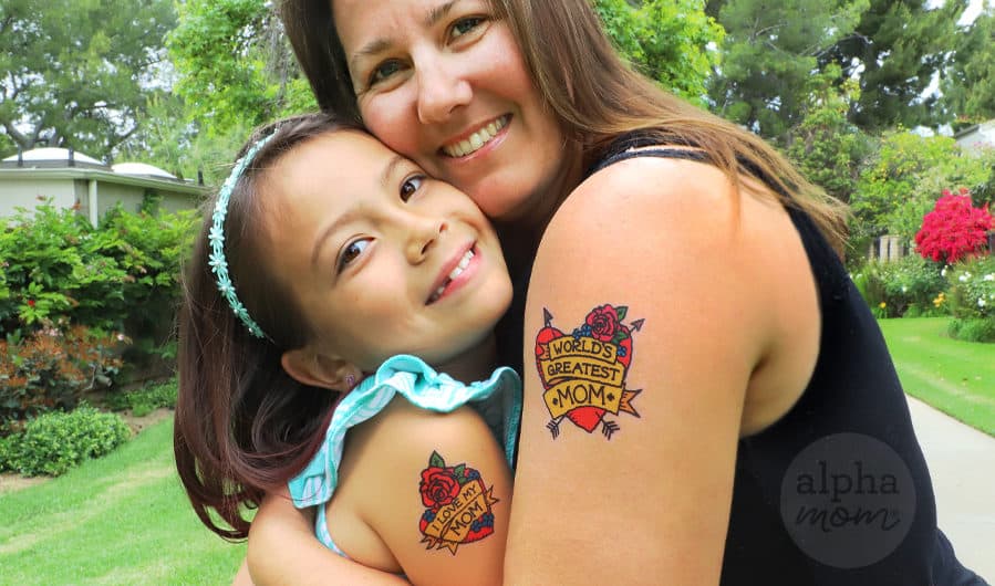 mother and daughter hugging who are showing wearing temporary tattoos on their arms that read World's Greatest Mom and I Love My Mom