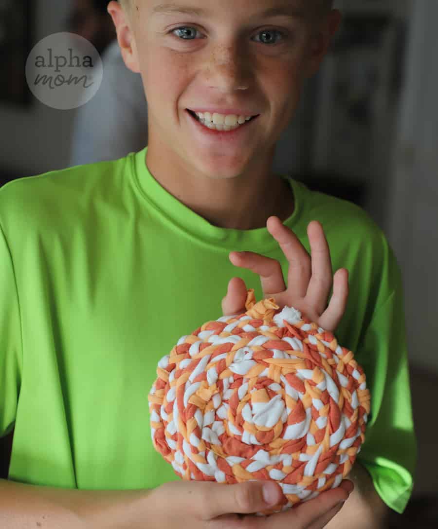 blond boy showing his completed upcylced potholder made of tie-dyed t-shirts