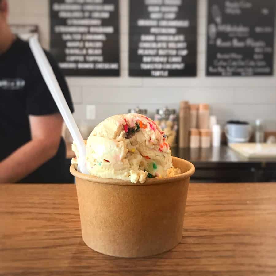 scoop of vanilla ice cream with sprinkles in paper cup on counter