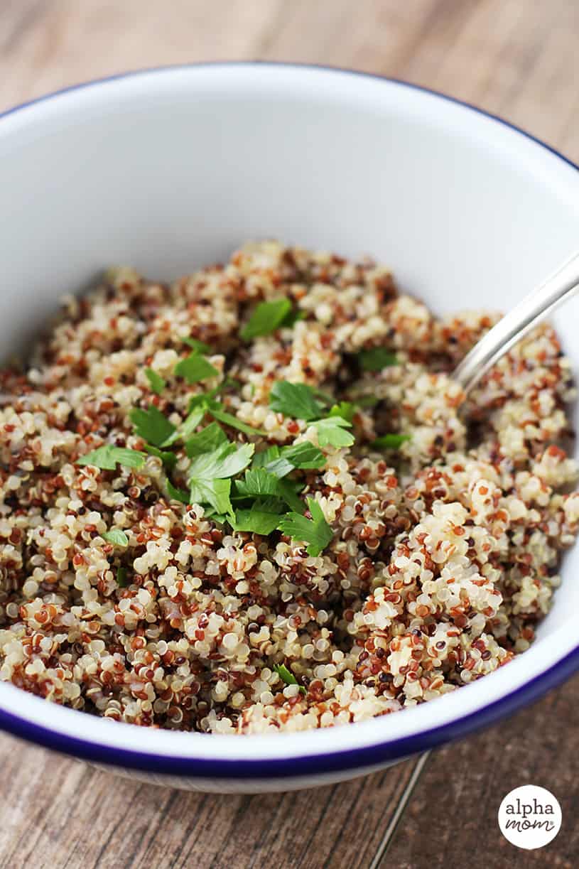 White bowl with cooked quinoa and parsley as a garnish