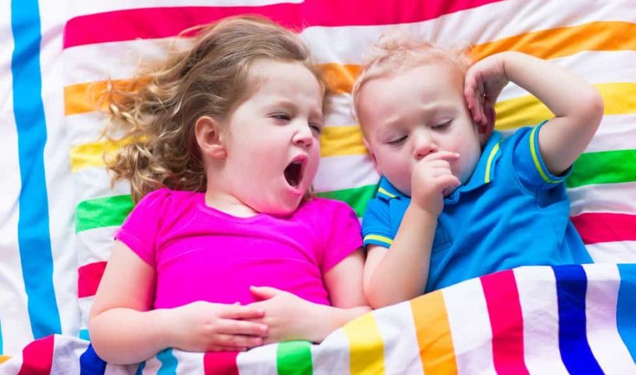 Children sleeping under colorful blanket