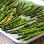 Side view of roasted asparagus on rimmed cookie sheet