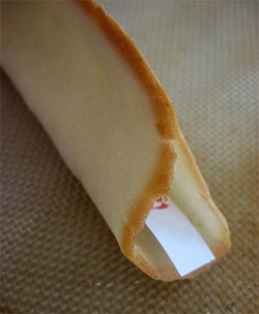 a homemade fortune cookie being made and a Happy New Year fortune being inserted