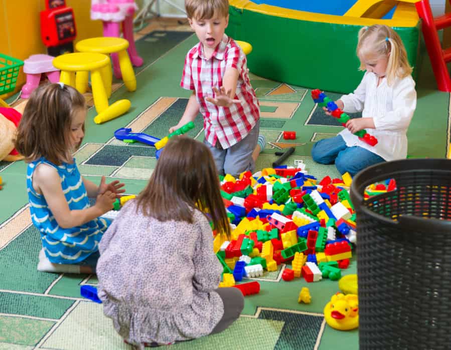 Group of kids playing with colorful Lego blocks on floor