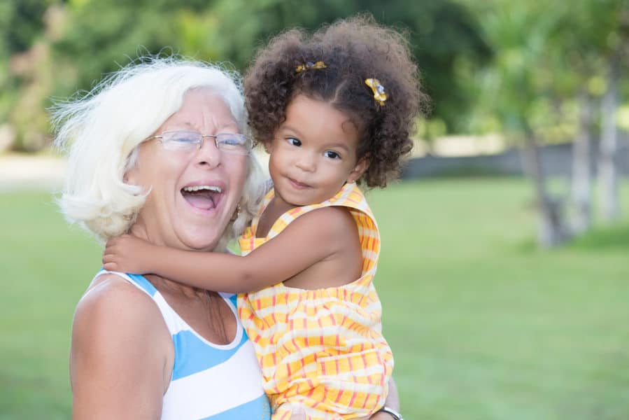 grandma carrying her toddler granddaughter and laughing