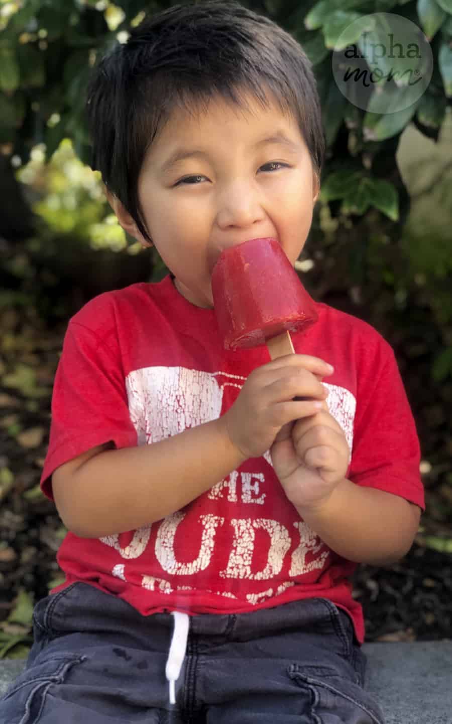 photo of young boy eating homemade strawberry watermelon popsicle 