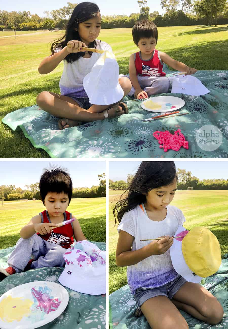 three pictures of two children sitting outdoors oric paintn blanket painting their white bucket hats with fab