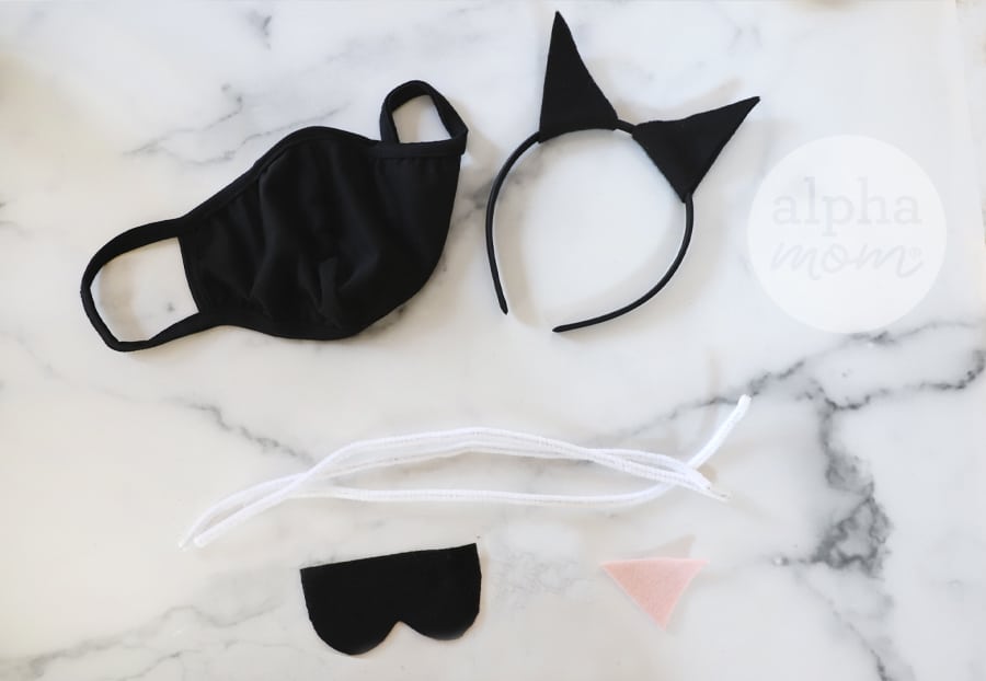 overhead photo of black cloth face mask, cat ear headband, and supplies to make cat costume 