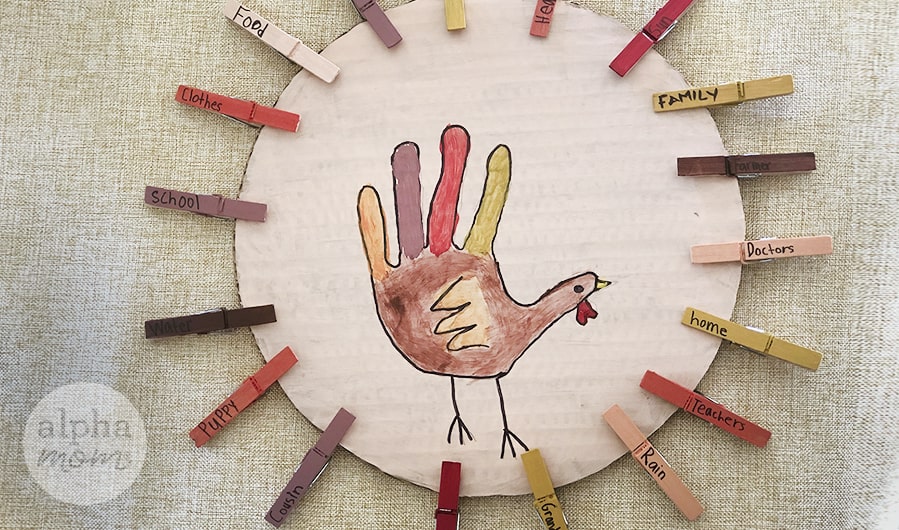 close-up overhead photo of cardboard gratitude chart with painted wooden clothespins with thankful words on them