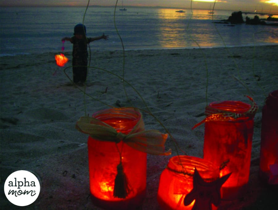 lit red lanterns in the sand by the ocean