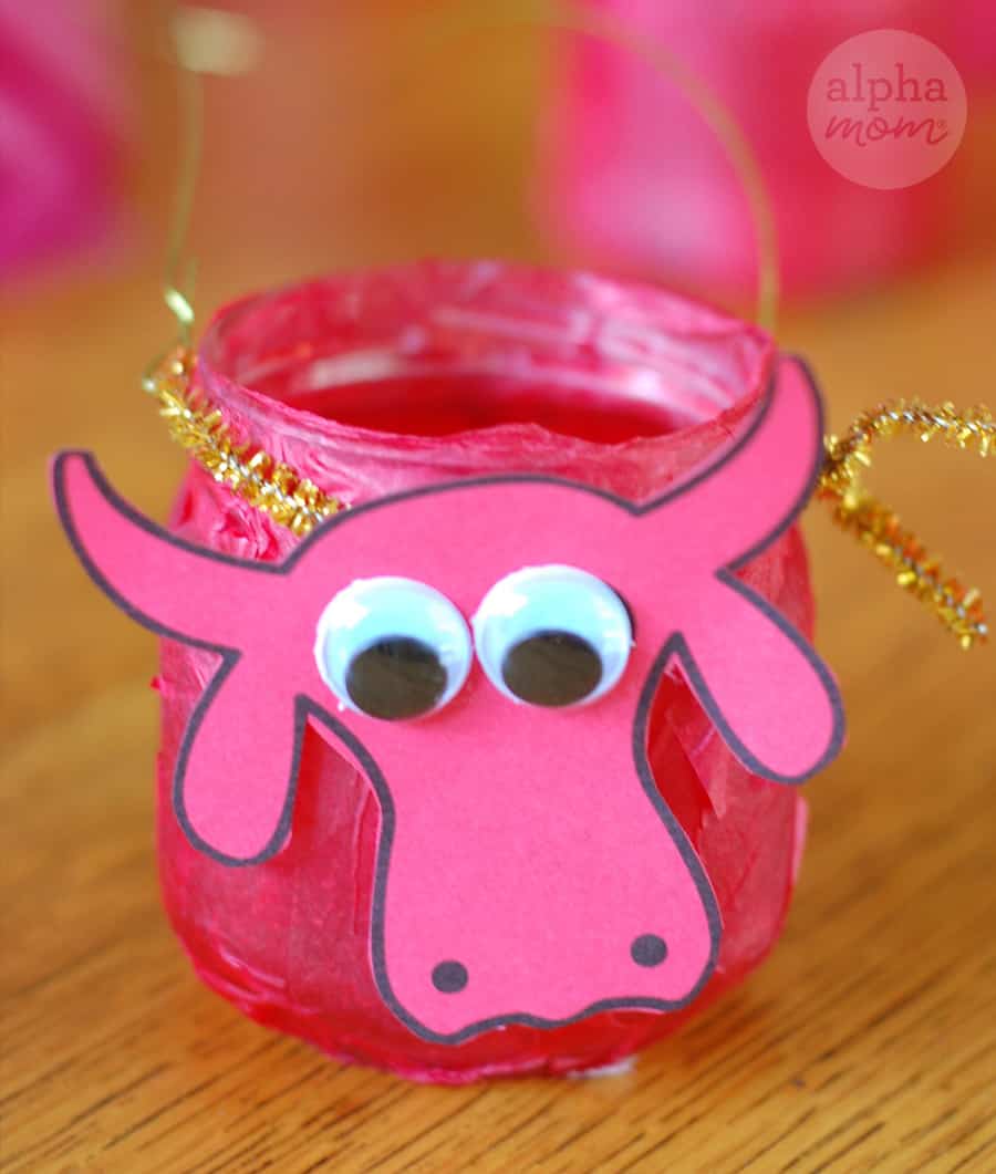 close-up photo of paper ox cutout over red decoupaged jar