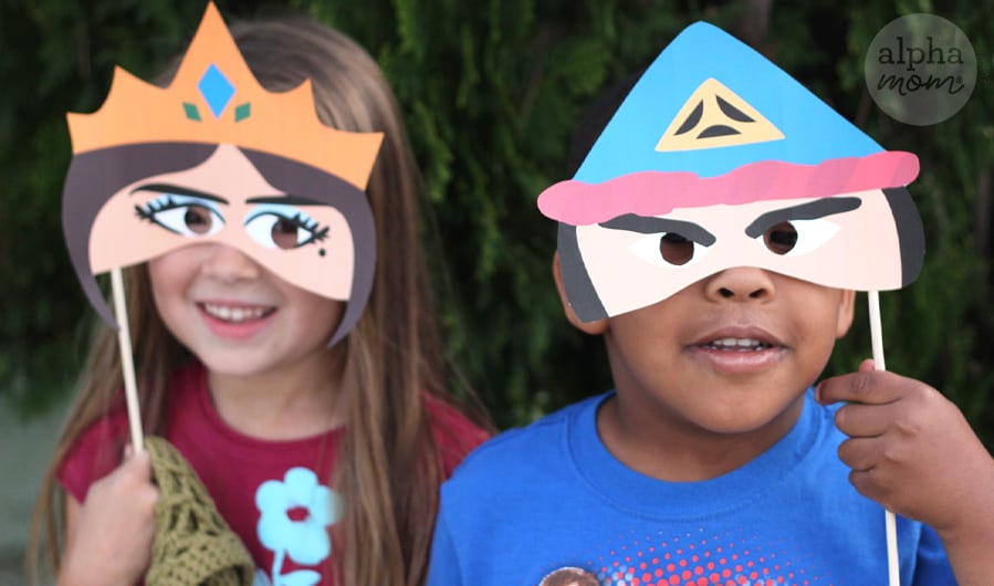 close-up photo of young girl holding up paper face mask of Queen Vashti and young boy covering his face with paper mask of Haman
