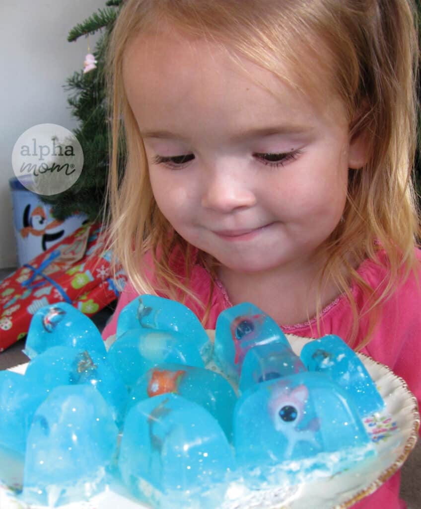 Young girl in pink shirt holding a tray with handmade Snowglobe soaps with toy reindeers in them