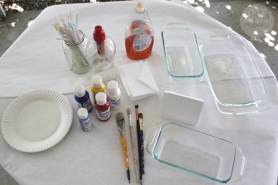 supplies for bubble fish art on tabletop (paint, brushes, straws, paper plates, soap, envelopes, baking dishes)